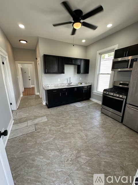 A kitchen with black cabinets and a ceiling fan.