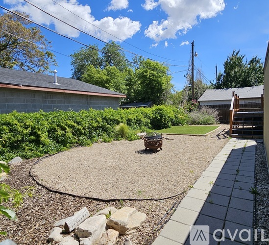 A backyard with a gravel area and a concrete walkway.