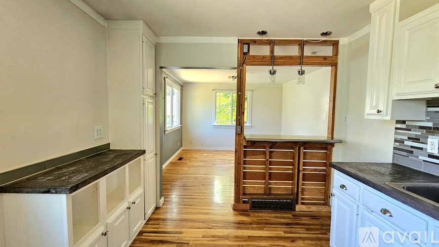 A kitchen with white cabinets and a black countertop is available for rent.
