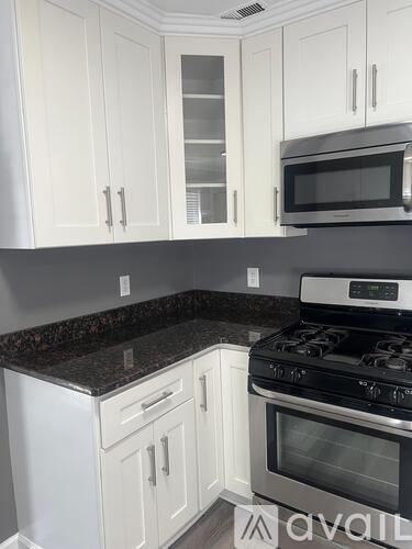 A kitchen with white cabinets and a black stove top.