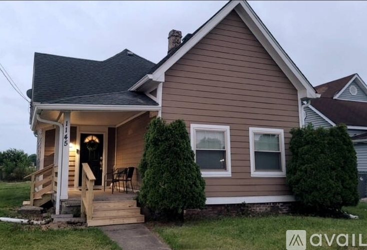 A house with a brown siding and a porch with a railing.