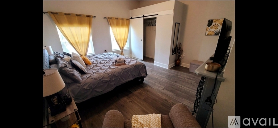 A bedroom with a bed, a chair, and a shelf with a mirror on it.