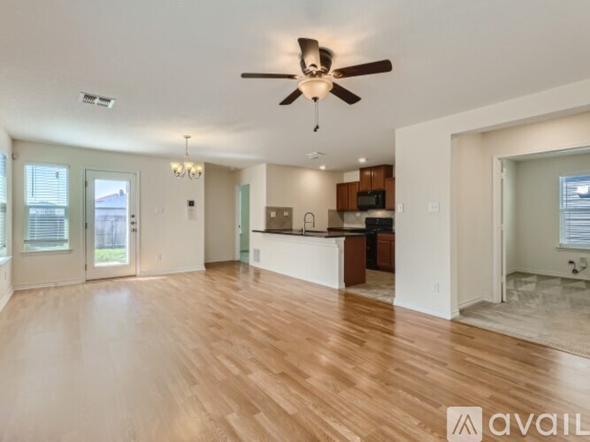 A spacious living room with a ceiling fan and hardwood floors.
