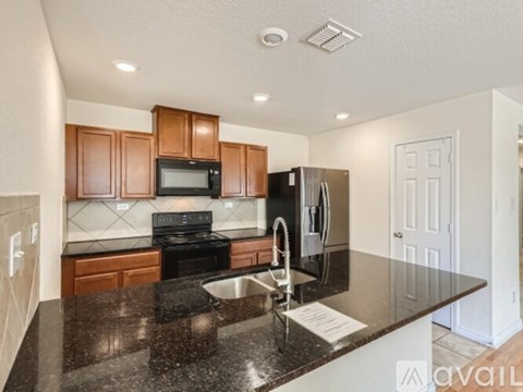 A kitchen with brown cabinets and a black granite countertop.