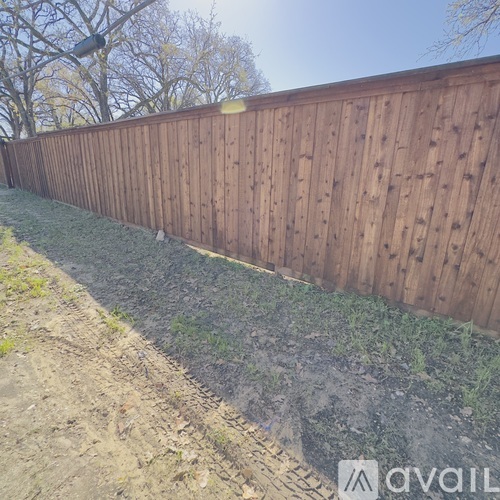 A wooden fence runs along the side of a grassy area.