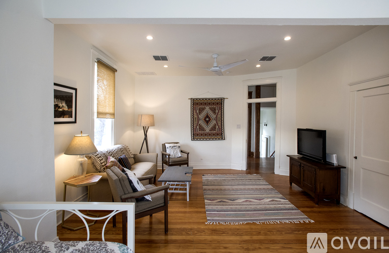 A living room with a sofa, a chair, a rug, a television, and a ceiling fan.
