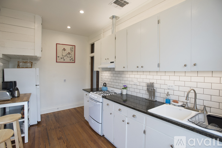 A kitchen with white cabinets and a black countertop.