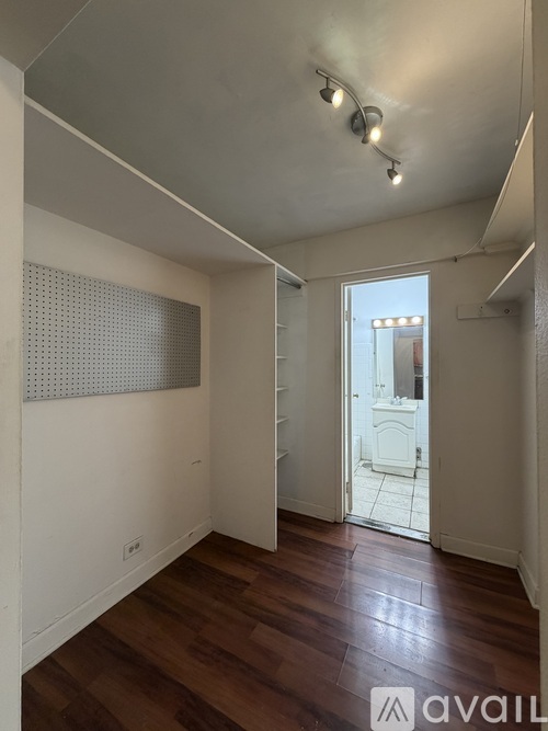 A room with wooden floors and a white wall with a perforated panel.
