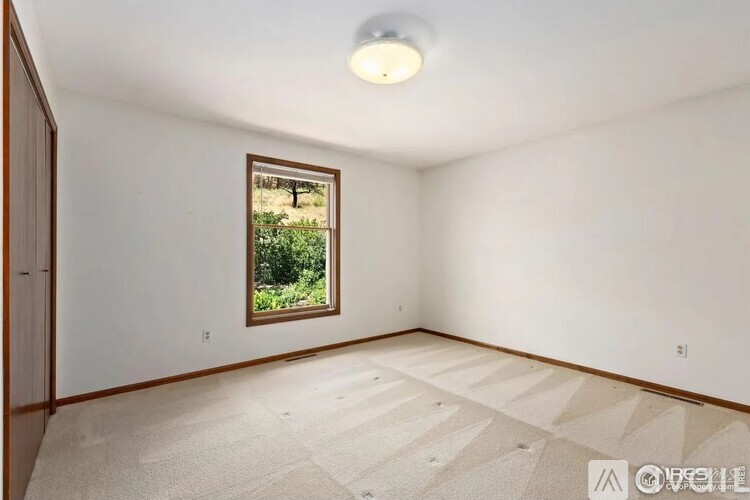 A room with a window and a carpeted floor.