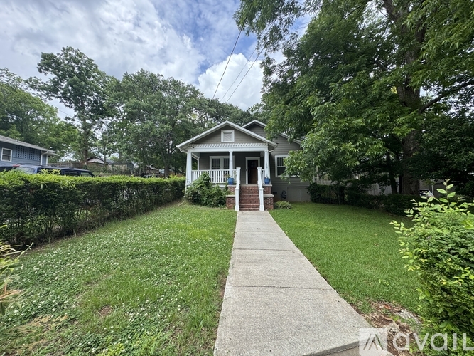 A house with a white porch and a concrete walkway leading to the front door.