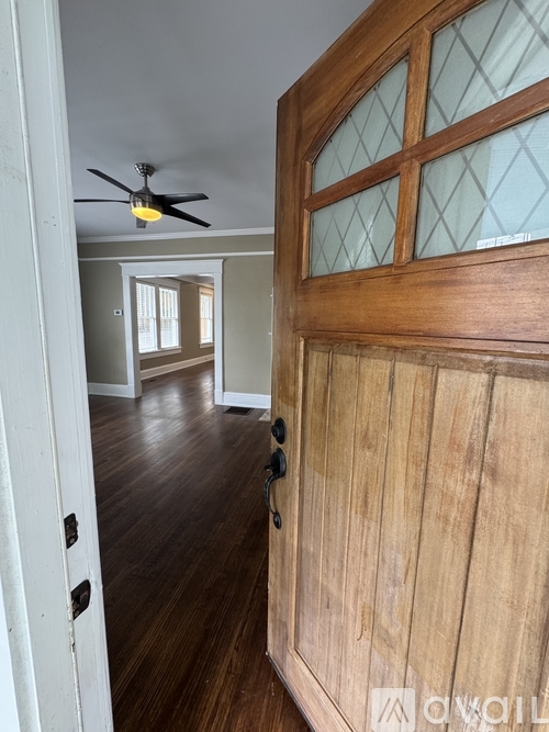 A room with a ceiling fan and a wooden door.