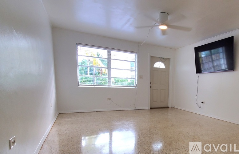 A room with a ceiling fan and a window with a view of a garden.