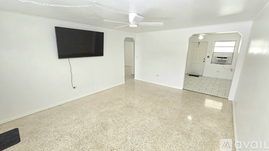 A room with a flat screen TV mounted on the wall and a ceiling fan.