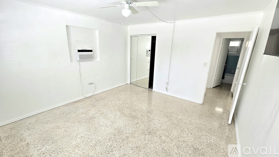 A spacious room with a ceiling fan and a white wall-mounted air conditioning unit.