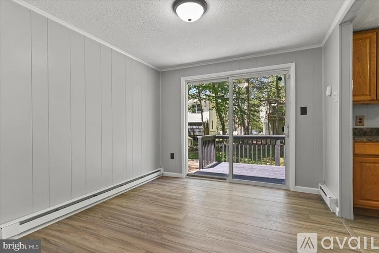 A bright, empty room with wooden floors and white walls leading to a balcony.