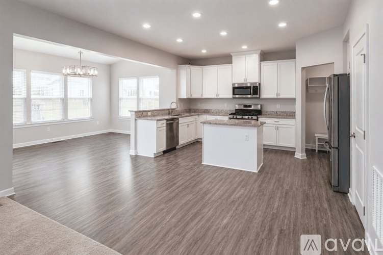 A spacious kitchen with white cabinets and a wooden floor.