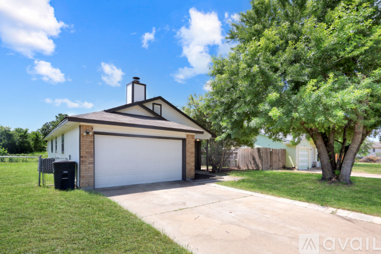 A house with a garage and a tree in front.