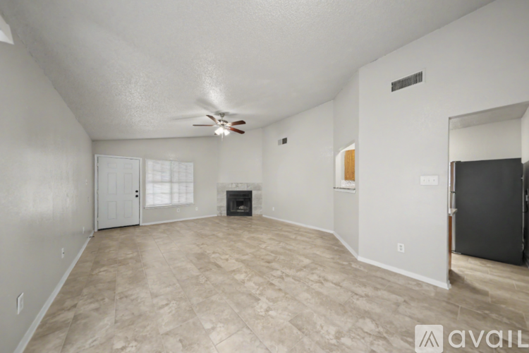 A spacious living room with a fireplace and a ceiling fan.