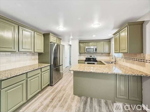 A kitchen with green cabinets and a granite countertop.