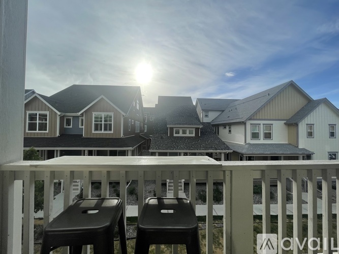 Two black chairs are on a white railing with houses in the background.