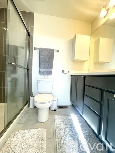 A white toilet sits in a bathroom with a glass shower door.