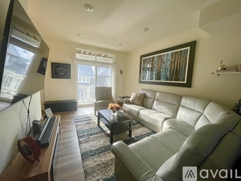A living room with a white leather couch and a wooden table.