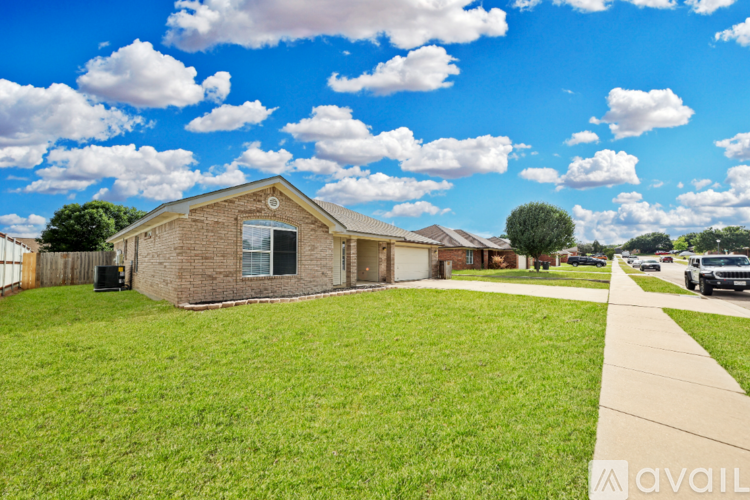 A house with a lawn in front and a cloudy sky above.