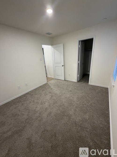 A carpeted room with a door on the right and a wall on the left.