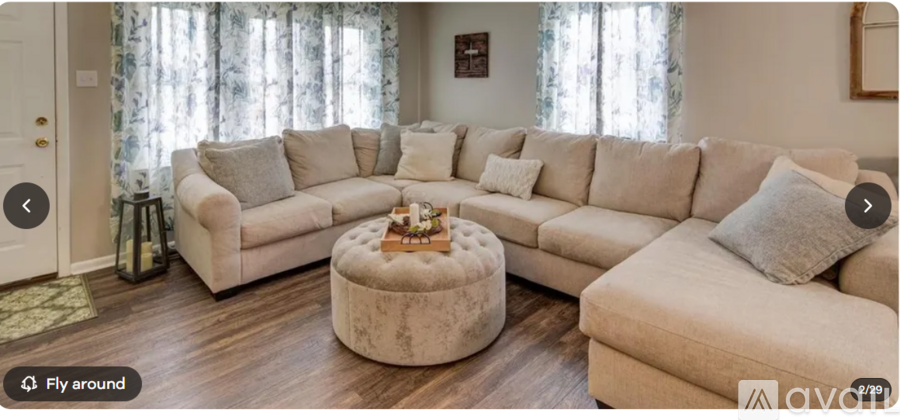 A living room with a large sectional sofa and a round ottoman.