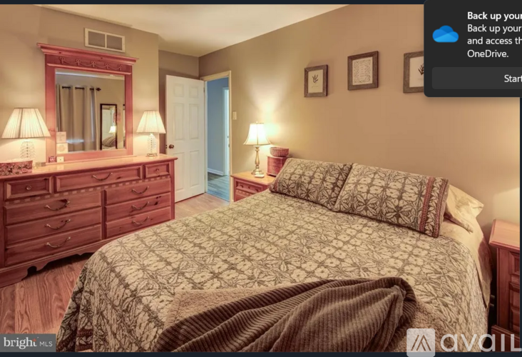 A bedroom with a bed, dresser, and mirror.