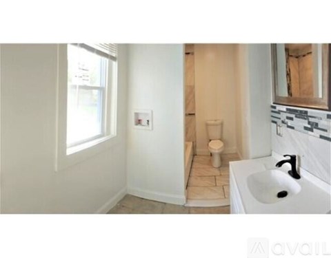 A bathroom with a toilet, sink, and window.