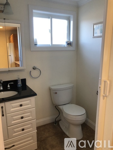 A bathroom with a toilet, sink, and cabinet.