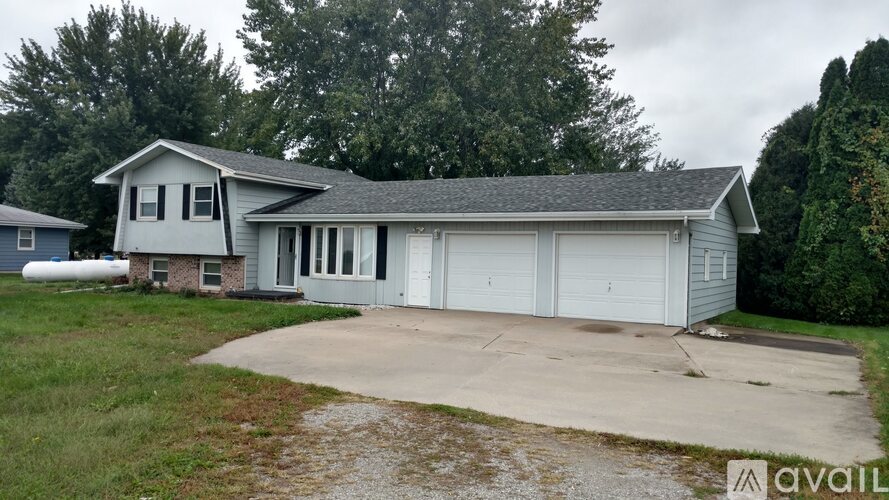 A house with a grey roof and a white garage door is available for sale.