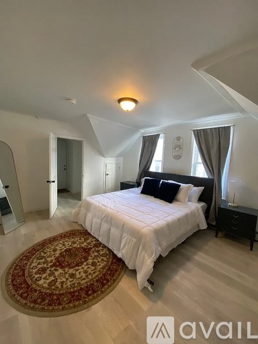 A bedroom with a large bed and a rug on the floor.