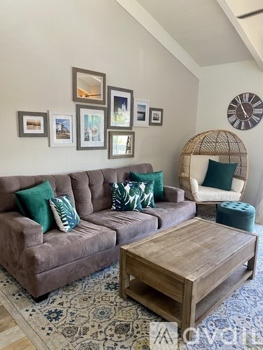 A living room with a brown couch, a wooden coffee table, and a wicker chair.