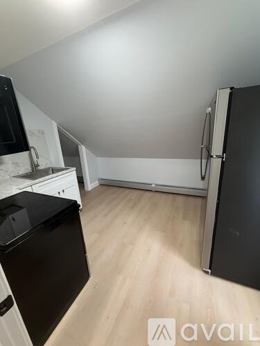 A kitchen with black appliances and wooden floors.