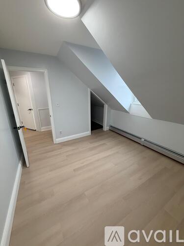 A room with a skylight and wooden flooring.