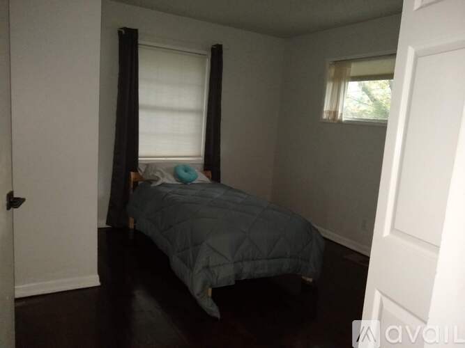 A bedroom with a bed and a window with blinds.