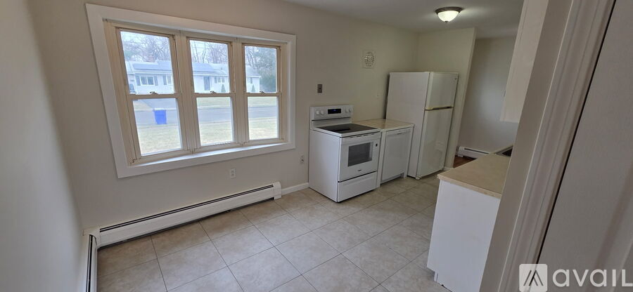 A kitchen with white appliances and a window.