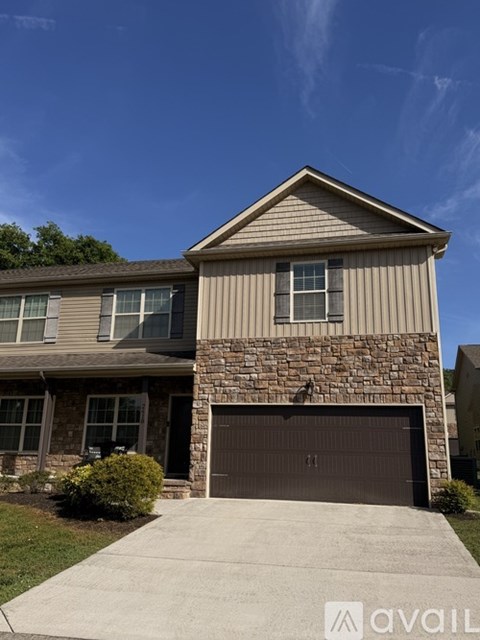 A house with a stone pillar and a brown garage door.