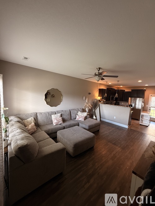 A living room with a grey couch and a round mirror on the wall.