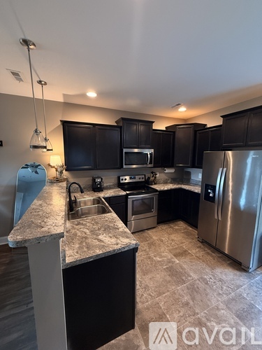 A kitchen with black cabinets and a marble countertop.