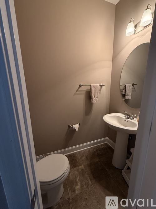 A bathroom with a toilet, sink, and mirror.