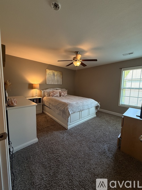 A bedroom with a bed, dresser, and window.