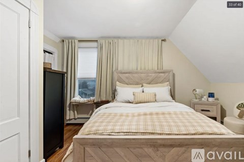 A bedroom with a large bed and a window with curtains.