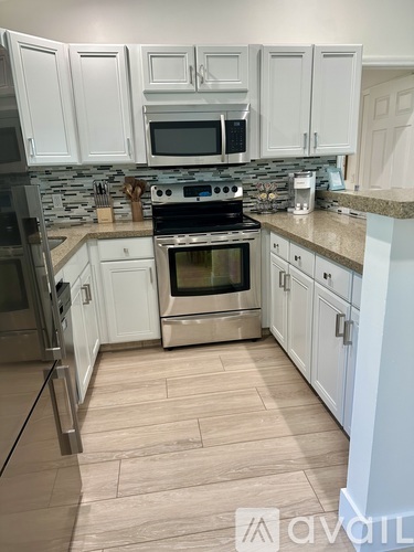 A kitchen with white cabinets and a stone backsplash.