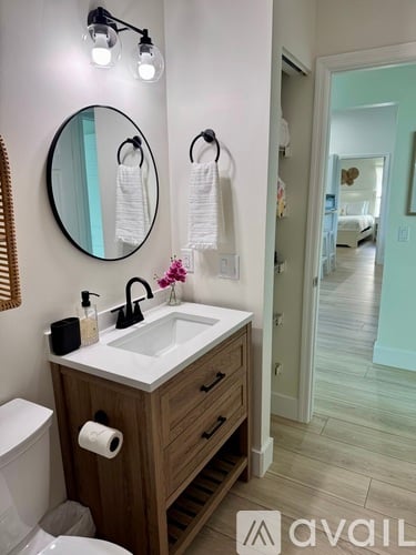 A bathroom with a sink, mirror, and towel rack.