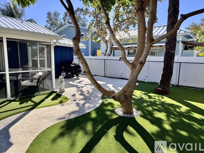 A tree in a yard with a house in the background.