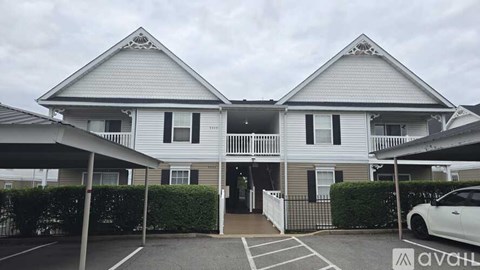 A two-story house with a carport and a white car parked in front.
