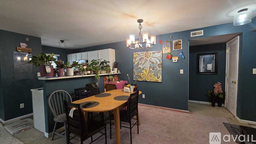 A dining room with a table set for six and a kitchen area with a refrigerator.